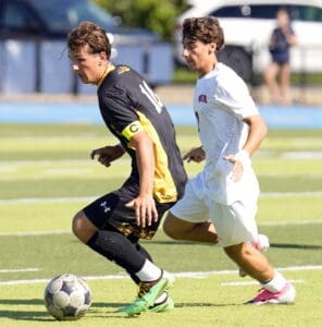 High school soccer players compete for the ball on the field, showcasing athleticism and teamwork during a match.
