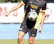 High school soccer player in action, wearing a black and yellow Tigers jersey, juggling a soccer ball on the field.