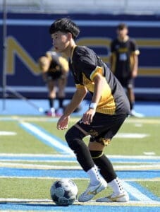 Young soccer player prepares to kick a ball during a game on a sunny field, focused and determined.