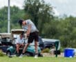 Young golfer in action, driving a ball on the fairway with golf carts in the background. Perfecting the swing technique.