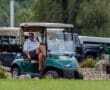 A man sitting in a golf cart on a lush green course, enjoying a sunny day at the golf club.