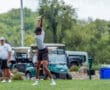 Young golfer preparing to swing a driver on the course, with golf carts visible in the background.