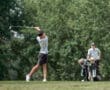 A golfer swings on the course, while a caddie carries golf bags in the background, surrounded by lush greenery.