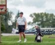 Young golfer walking on the course, carrying a golf bag, prepares for his next shot under a cloudy sky.