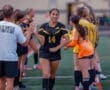 Team players celebrate as a soccer player in a black jersey receives a high-five before the game. Team spirit and motivation shine.
