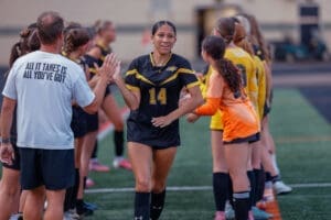 Team players celebrate as a soccer player in a black jersey receives a high-five before the game. Team spirit and motivation shine.