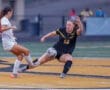 Two female soccer players compete for the ball on the field, showcasing skill and intensity during the match.