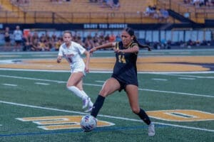 Two female soccer players competing on the field during a match, one in black, the other in white.