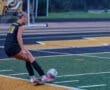 Soccer player in action, preparing to kick a ball on a colorful turf field during a game.