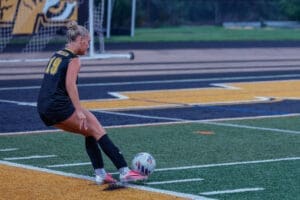 Soccer player in action, preparing to kick a ball on a colorful turf field during a game.