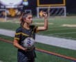 Soccer player signaling while holding a ball on a well-lit field, ready for play during a night match.