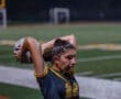 A female soccer player wearing jersey number 22 prepares to throw the ball in a nighttime match on the field.
