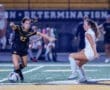 Two female soccer players compete for the ball during a night game, highlighting athleticism and sportsmanship on the field.
