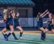 Girls' soccer team celebrates a victory under the stadium lights, showcasing teamwork and joy on the field.