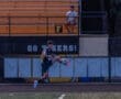 A soccer player performs a kick on the field, with spectators watching in the background. Go Tigers! visible.