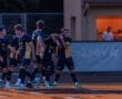 High school soccer team celebrating a goal, showcasing teamwork and camaraderie on the field during a game.