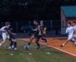 Players compete in a nighttime high school soccer match, showcasing dynamic action on the field.