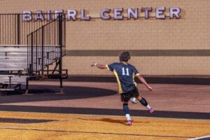 A player in a black and yellow soccer uniform prepares for a throw-in at the Baierl Center stadium.