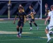 High school soccer players compete on the field during a nighttime match, showcasing teamwork and athleticism.