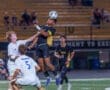High school soccer match where a player executes a header while opposing players defend. Excitement on the field!