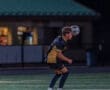 Young soccer player heading a ball during a night game on a well-lit field, showcasing athletic skill and focus.