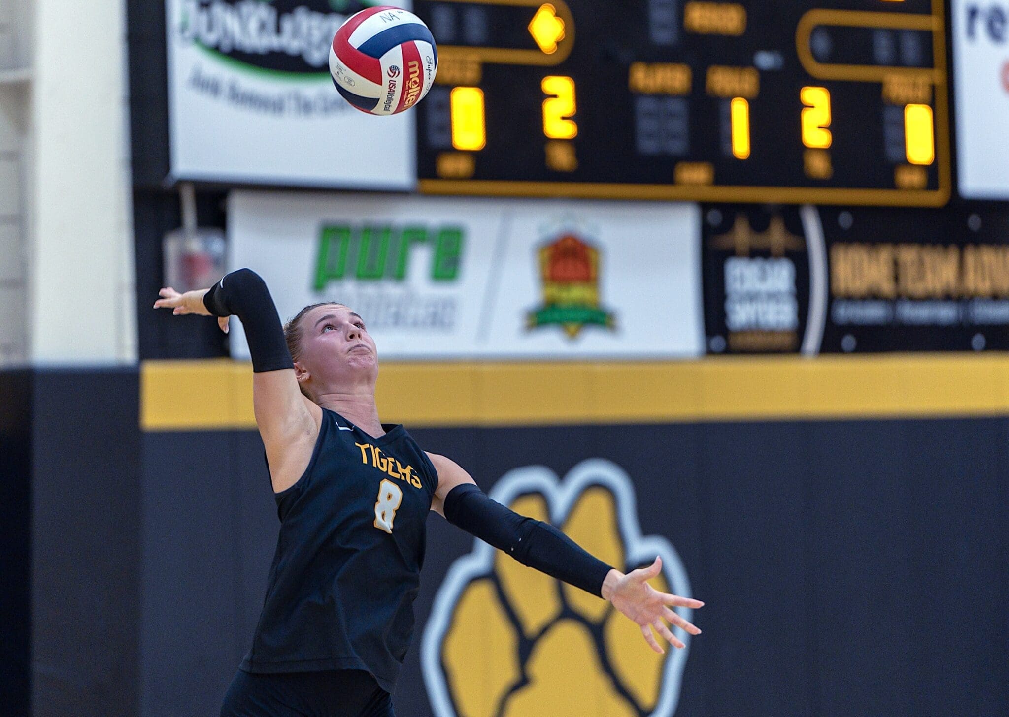 A volleyball player serves the ball during a game, showcasing athletic skill and team spirit in action.