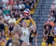 Volleyball player sets the ball in front of a cheering crowd during a competitive match in a vibrant gymnasium.