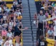 Volleyball player spikes the ball during a match, with a focused referee overseeing the exciting game.