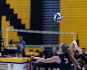 A volleyball player prepares to serve during a match, showcasing athleticism and focus in a competitive setting.