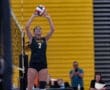 Volleyball player prepares to set the ball during a match, showcasing teamwork and athleticism on the court.