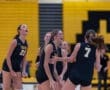 Girls' volleyball team celebrating a point in a spirited game, showcasing teamwork and enthusiasm on the court.