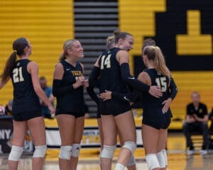 Team huddling during a volleyball match, celebrating and strategizing in a vibrant gym setting.