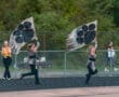 Two performers wave large flags with paw prints at a sports event, showcasing school spirit and choreography.