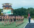 North Allegheny cheerleaders perform on Wright Field as the scoreboard displays game details and a vibrant crowd scene.