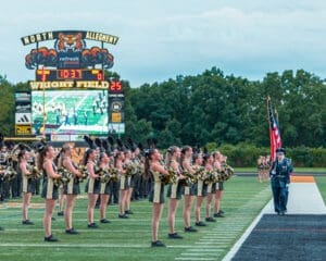 North Allegheny cheerleaders perform on Wright Field as the scoreboard displays game details and a vibrant crowd scene.