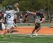 Quarterback #15 throws a pass under pressure from a defender in a high school football game on a turf field.