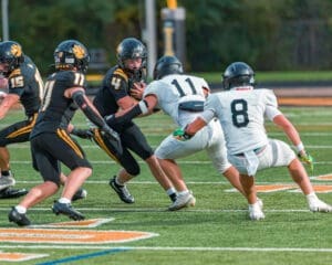 High school football players in action, with one player dodging tackles on a vibrant field during a competitive game.