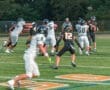 High school football players in action; one quarterback throws a pass amid defensive pressure on the field.