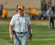 Coach on the field wearing a headset and team gear, focused on the game during a football match.