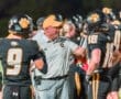 Football coach guiding players during a game, highlighting teamwork and strategy on the field.