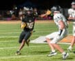 Football player #16 dodges opponents on the field during a night game, showcasing athleticism and skill.