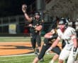 Quarterback throwing a football during a high school football game on a night filled with action.