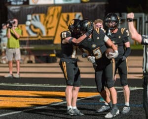 Players celebrating a touchdown on the field, showcasing teamwork and excitement in a high school football game.