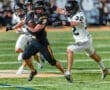 High school football player #2 evades a tackle from player #32 during an intense night game on the field.