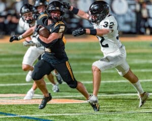 High school football player #2 evades a tackle from player #32 during an intense night game on the field.