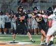 High school quarterback throws a pass under pressure during a night football game on the field.
