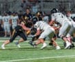 High school football players compete during a night game on the field, showcasing intense action and teamwork.
