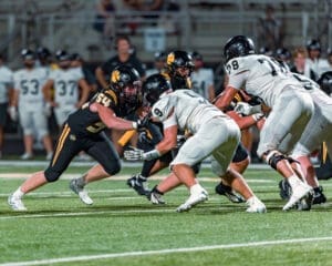High school football players compete during a night game on the field, showcasing intense action and teamwork.