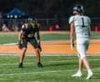 High school football players in action under stadium lights, showcasing competitive play on the field at night.