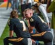 Two football players discuss strategies on the sidelines during a game, showcasing teamwork and focus in sports.